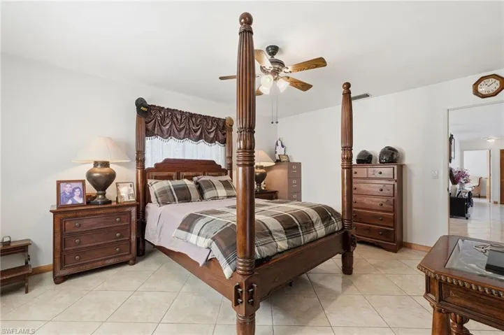 Spacious room featuring neutral wall tones, large format tile flooring, a ceiling fan with integrated lighting, and a wide doorway opening to an additional interior space