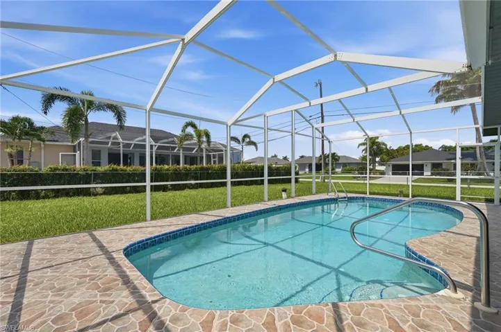 Screened pool area featuring a freeform swimming pool with integrated steps and handrails