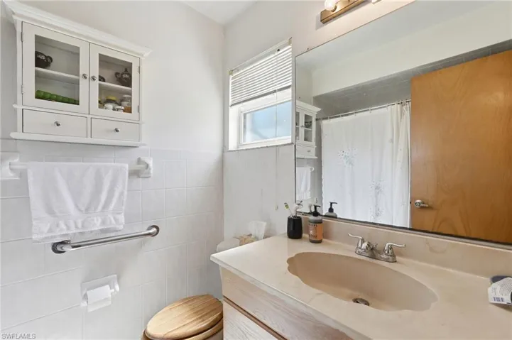 Bathroom featuring a single vanity with an integrated scalloped sink and a full-width mirror