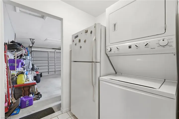 White stackable washer and dryer unit, complemented by a refrigerator