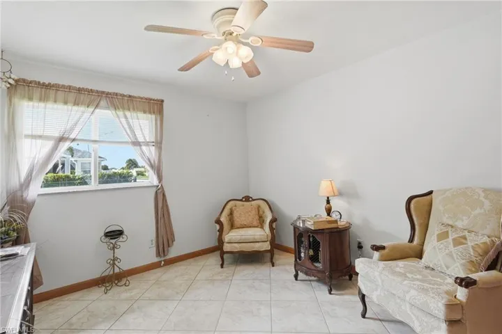 Bright room featuring a window with white blinds, neutral wall paint, and a ceiling fan with integrated lighting