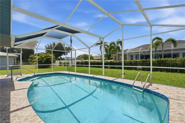 Screened-in outdoor pool featuring a freeform design, integrated steps, and a tiled edge