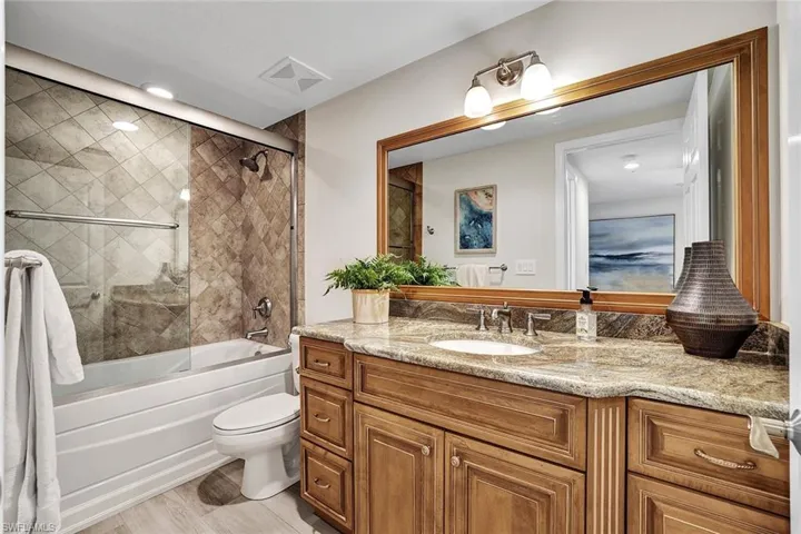 Full bathroom featuring vanity, wood-type flooring, bath / shower combo with glass door, and toilet