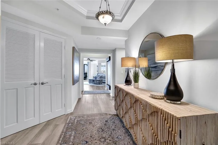 Hallway with light hardwood / wood-style flooring, a raised ceiling, and crown molding