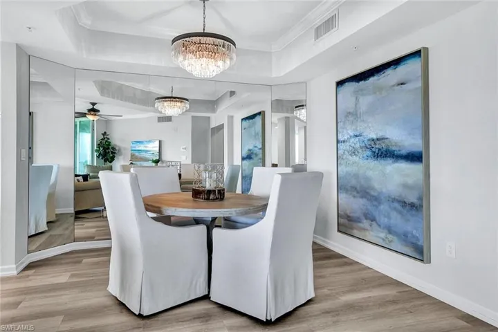 Dining space featuring light hardwood / wood-style flooring, a raised ceiling, and ceiling fan with notable chandelier