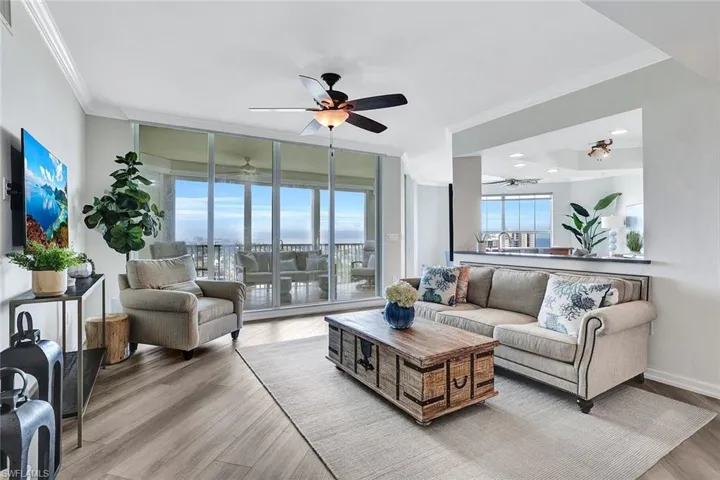Living room featuring a wall of windows, crown molding, ceiling fan, and light hardwood / wood-style floors