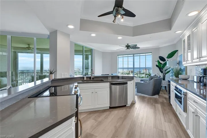 Kitchen featuring ceiling fan, light hardwood / wood-style flooring, stainless steel appliances, and a tray ceiling