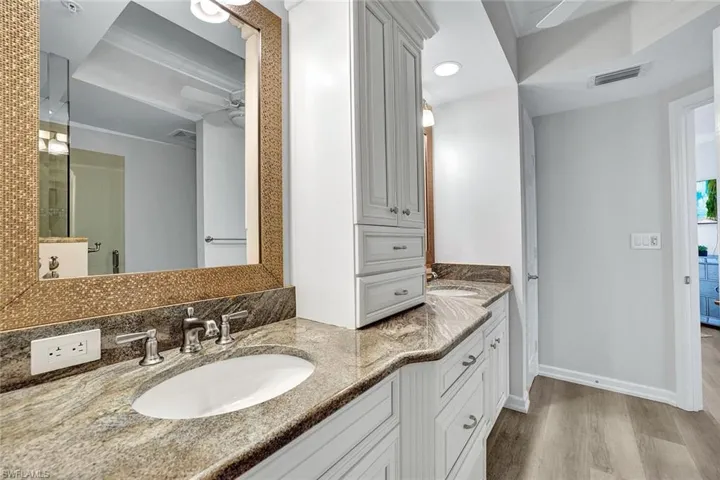 Bathroom featuring double sink vanity, crown molding, wood-type flooring, and ceiling fan