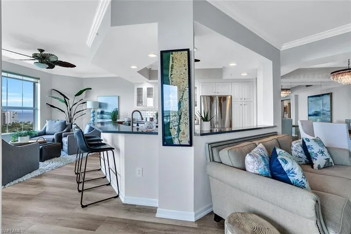 Kitchen featuring ceiling fan, white cabinets, crown molding, stainless steel fridge, and light wood-type flooring