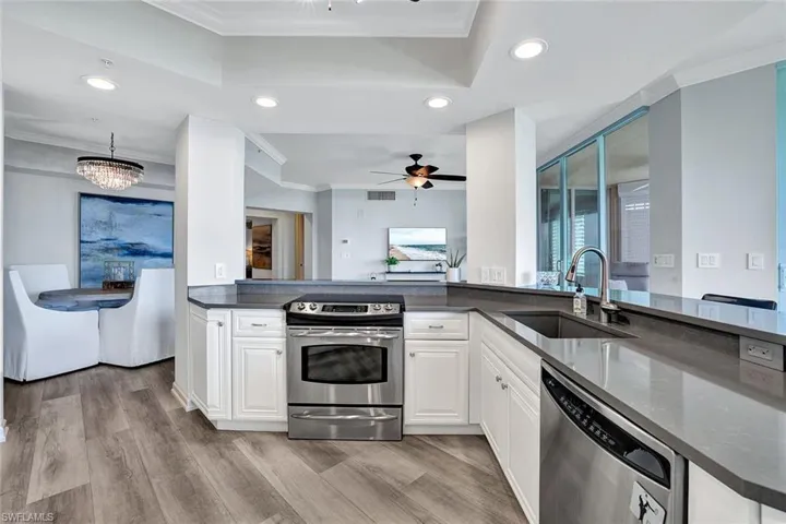 Kitchen with ceiling fan with notable chandelier, stainless steel appliances, light hardwood / wood-style floors, sink, and white cabinets