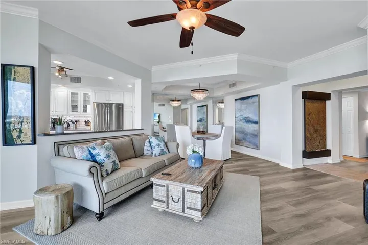 Living room featuring ceiling fan, crown molding, and wood-type flooring