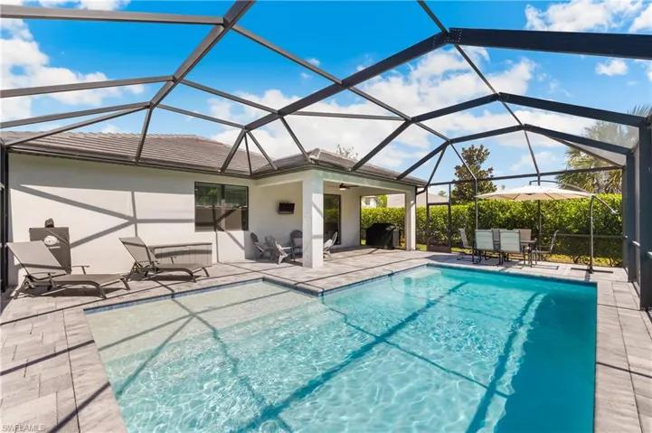 Outdoor pool with a patio area, outdoor dining area, and glass enclosure