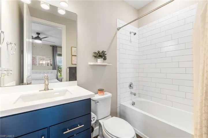 Bathroom with shower / bath combination with curtain, vanity, ensuite bathroom, and ceiling fan