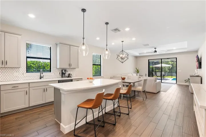 Kitchen with open floor plan, a center island, wood finished floors, light countertops, and recessed lighting