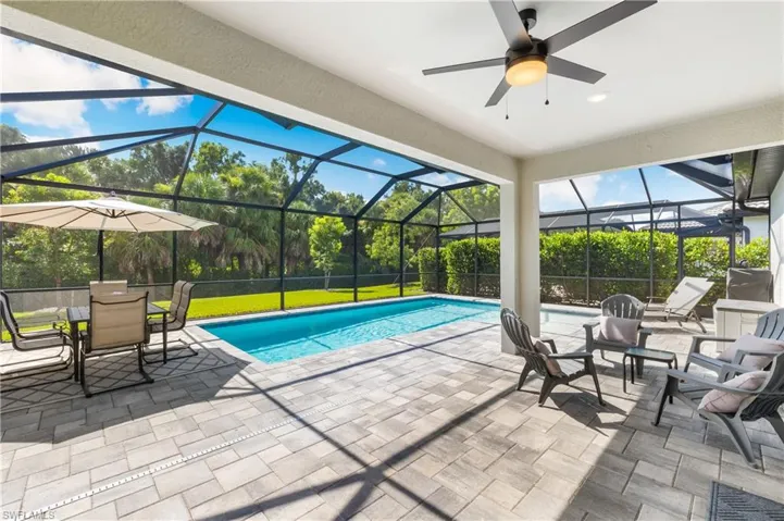 Swimming pool with a patio area, glass enclosure, and ceiling fan