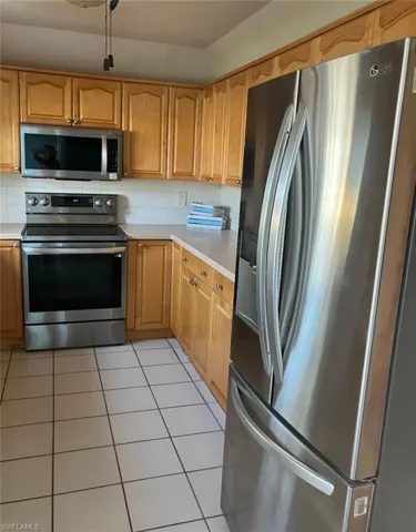Kitchen featuring appliances with stainless steel finishes, light countertops, decorative backsplash, and light tile patterned floors