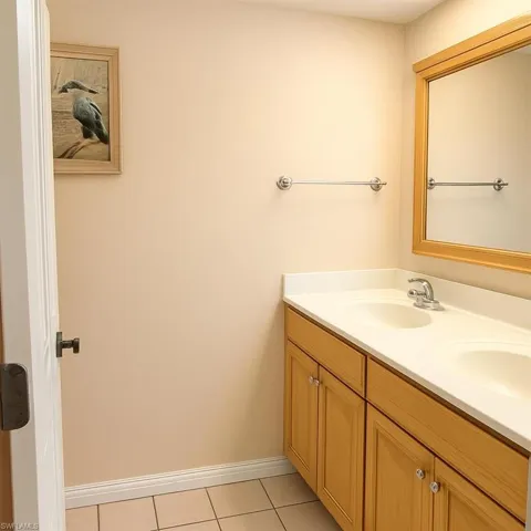 Bathroom with double vanity and light tile patterned floors