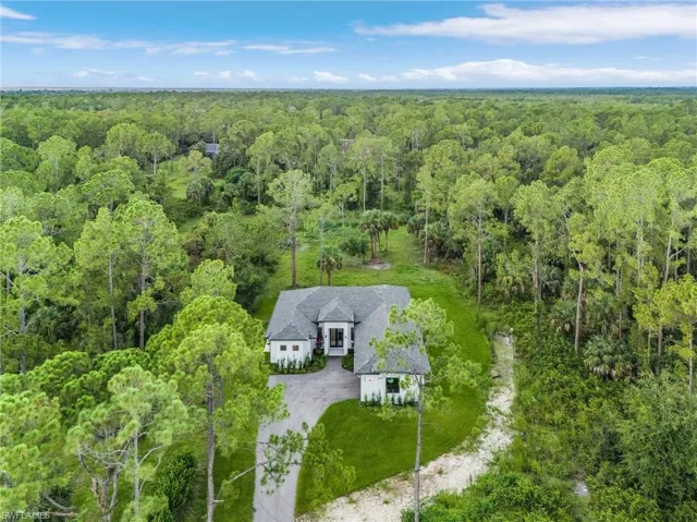 Aerial view of property and surrounding area with a heavily wooded area