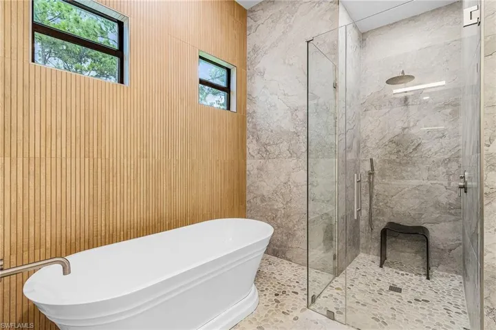 Bathroom with a freestanding tub and a marble finish shower