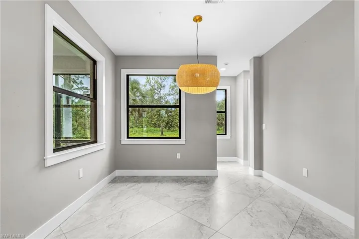 Unfurnished dining area with light marble finish flooring and baseboards
