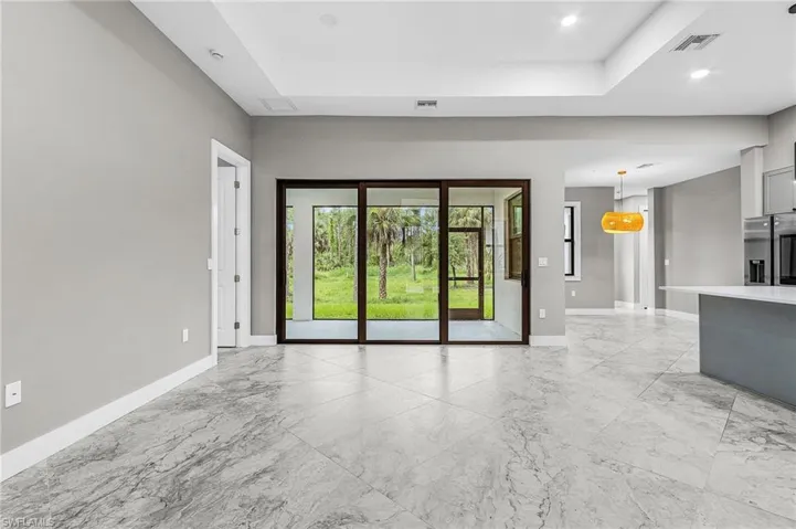 Spare room with a raised ceiling, light marble finish floors, and recessed lighting