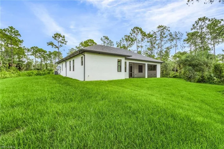 Back of property featuring a yard and stucco siding