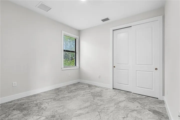 Unfurnished bedroom with light marble finish floors and a closet