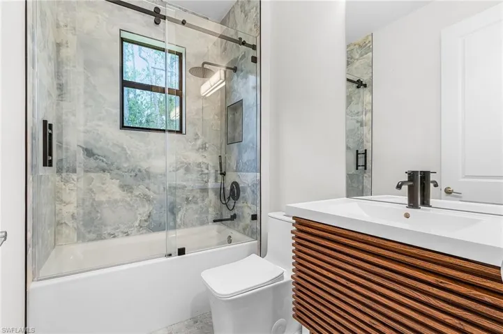 Bathroom featuring vanity and bath / shower combo with glass door