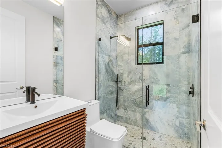 Bathroom with vanity and a marble finish shower