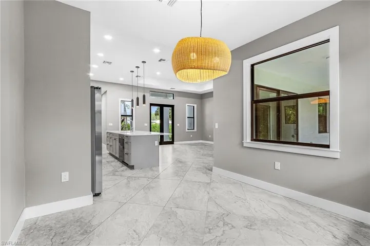 Kitchen with decorative light fixtures, a center island with sink, light marble finish floors, recessed lighting, and light stone countertops