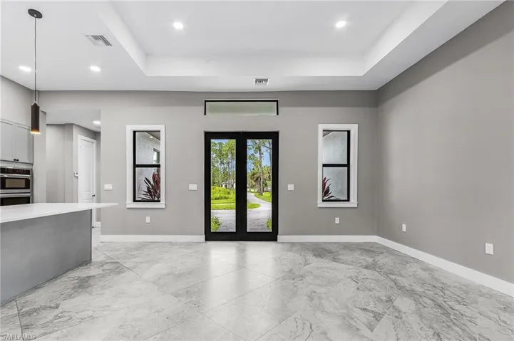 Foyer featuring a tray ceiling, light marble finish floors, and recessed lighting