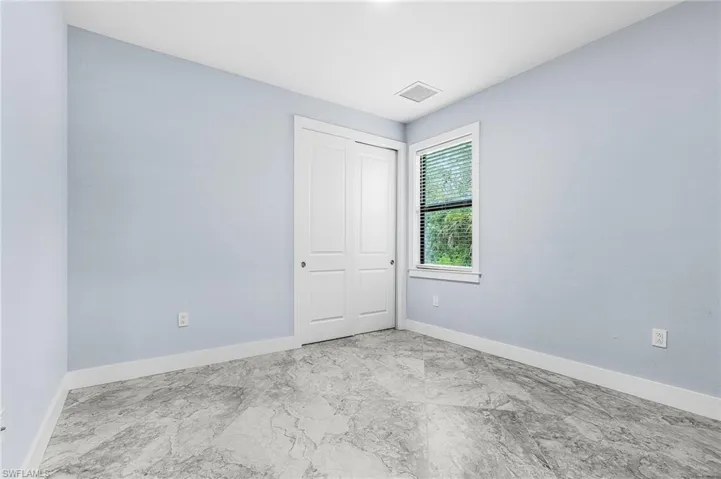 Unfurnished bedroom with a closet and marble finish floors