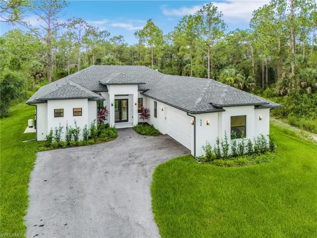 View of front of home featuring a garage, stucco siding, a front lawn, and roof with shingles