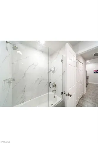 Bathroom with tiled shower / bath and hardwood / wood-style floors