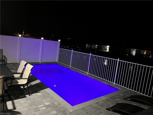 Pool at night featuring a patio