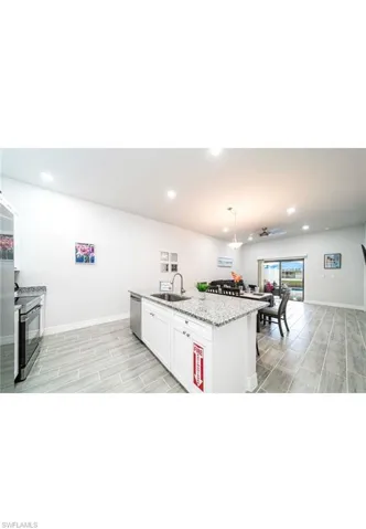 Kitchen with white cabinets, decorative light fixtures, appliances with stainless steel finishes, sink, and a center island with sink
