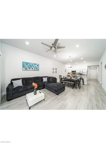 Living room with light hardwood / wood-style flooring, ceiling fan, and vaulted ceiling