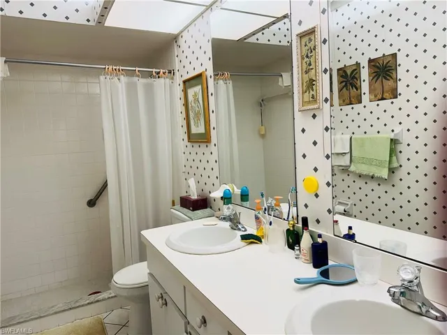Bathroom with a shower with curtain, vanity, toilet, and tile patterned floors