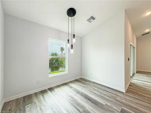 Unfurnished dining area with lofted ceiling, light wood finished floors, and a water view