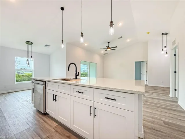 Kitchen featuring hanging light fixtures, white cabinets, a center island with sink, light wood finished floors, and recessed lighting