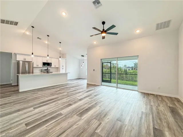 Unfurnished living room featuring high vaulted ceiling, light wood finished floors, a ceiling fan, and recessed lighting