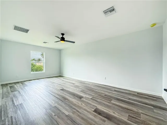 Spare room with dark wood-type flooring and a ceiling fan