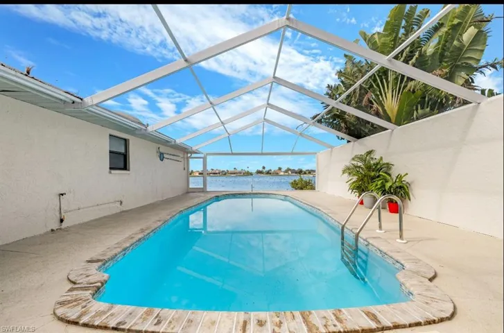 Swimming pool with a lanai, a sunroom, a patio, and a water view