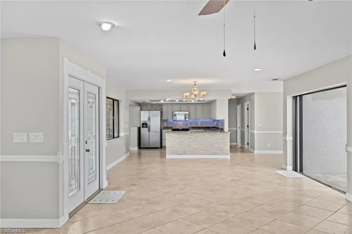 Kitchen with appliances with stainless steel finishes, open floor plan, light tile patterned floors, recessed lighting, and a chandelier