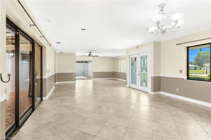 Spare room with french doors, a ceiling fan, light tile patterned flooring, and a chandelier