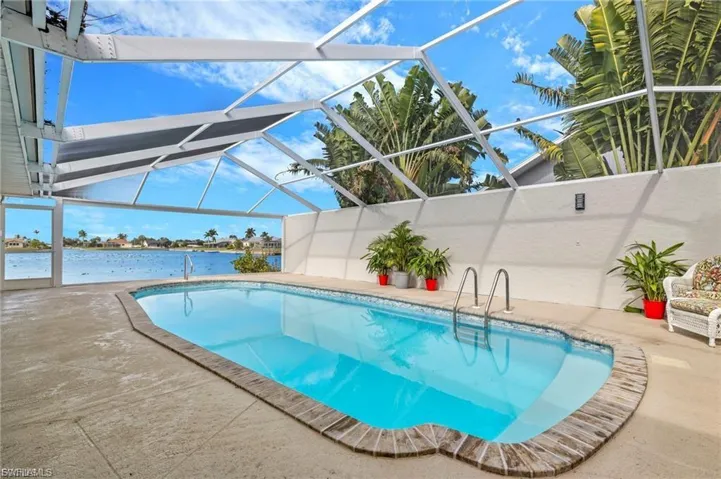 Swimming pool with a water view, a sunroom, a patio area, and a lanai