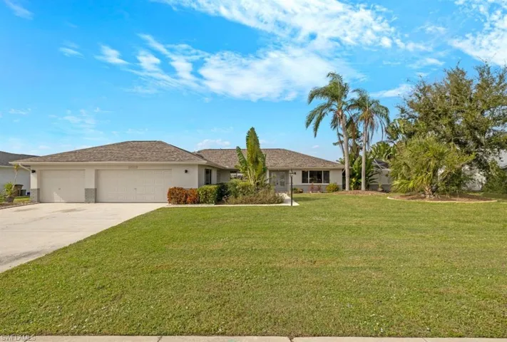 Ranch-style home with a front lawn, driveway, an attached garage, and stucco siding