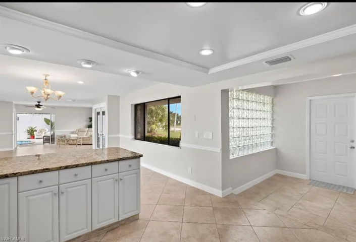 Kitchen with dark stone countertops, white cabinetry, light tile patterned floors, recessed lighting, and pendant lighting