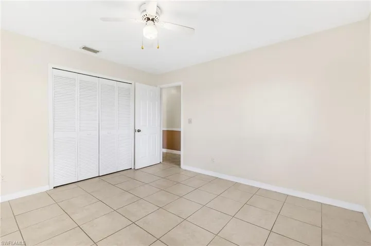 Unfurnished Guest bedroom with a ceiling fan, light tile patterned floors, and a closet
