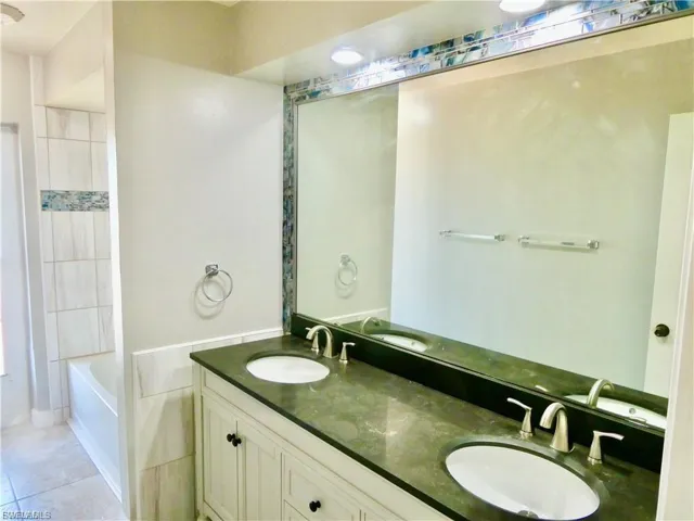 Full bath featuring double vanity and light tile patterned flooring